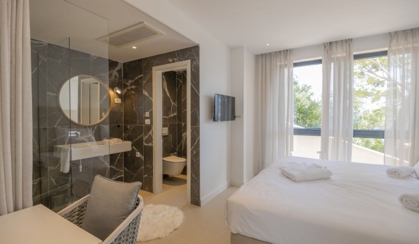 View of the double bed and en suite bathroom in the bedroom in a modern villa with a view of the sea in Brela