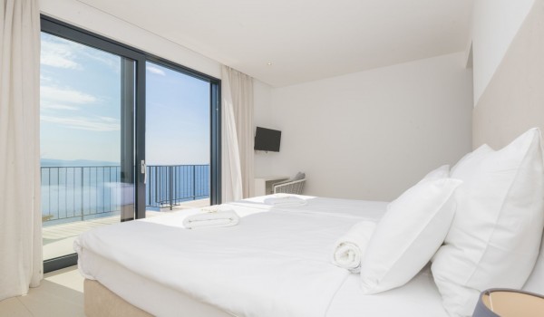 A balcony with a view of the sea, a double bed and an LCD TV in the bedroom in a luxury holiday villa with a private pool in Brela