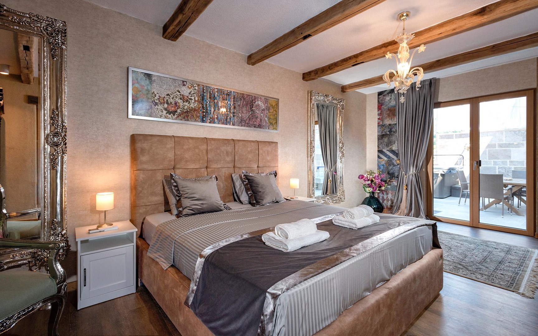 A bedroom with a comfortable double bed, a mirror and direct access to the outdoor terrace of the luxurious villa Castello Hvar in the center of Hvar