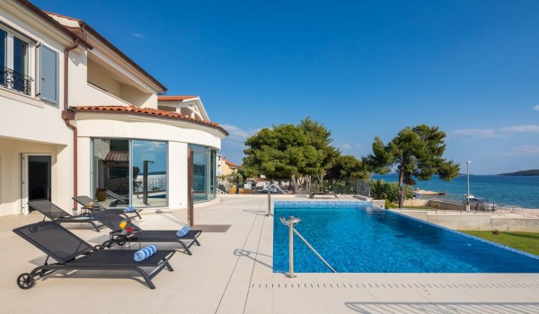 Deck chairs by the outdoor pool of the luxury seafront villa for family vacation in Sibenik