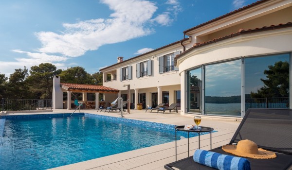 Deck chairs by the outdoor pool of the luxury seafront villa for family vacation in Sibenik