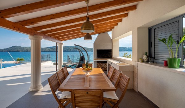 Outdoor dining area with traditional grill in the luxury vacation villa by the sea in Sibenik