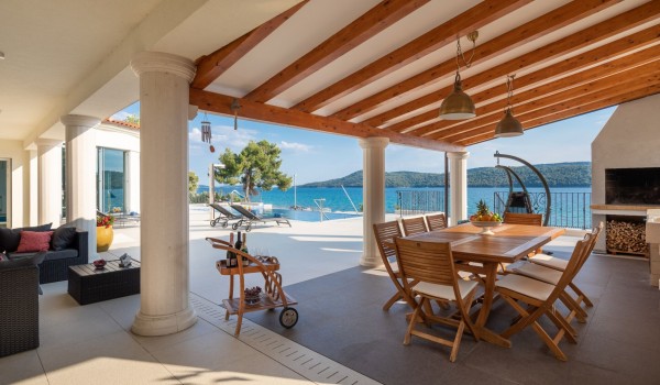 Outdoor dining area with traditional grill in the luxury vacation villa by the sea in Sibenik