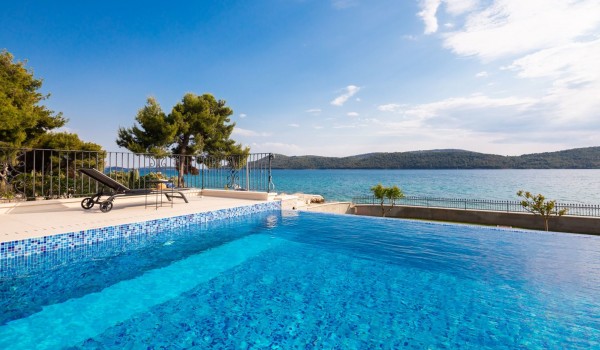 Outdoor infinity pool overlooking the sea in the luxury beachfront villa with concierge service in Sibenik
