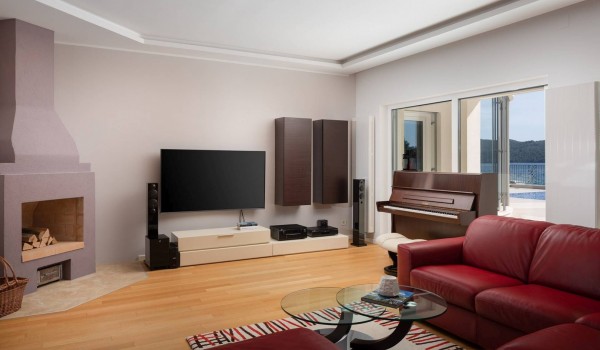 Living room with piano, fireplace and big TV in a luxury seafront villa for vacation with friends in Sibenik
