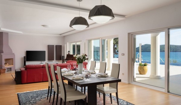 Dining table and large sofa in the living room with direct entrance to the terrace of the Luxury holiday villa with concierge service and private indoor heated pool