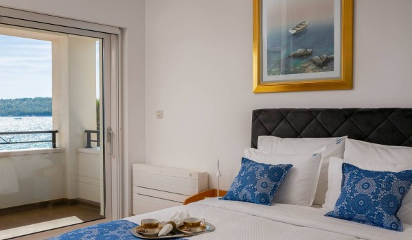 Queen size bed in a bedroom with private terrace of the beachfront villa with sauna, gym and jacuzzi in Sibenik