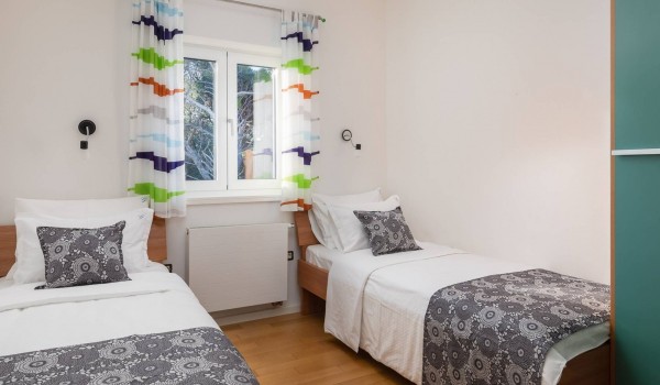 Two single beds in a bedroom of a luxury family villa for holiday by the sea in Sibenik