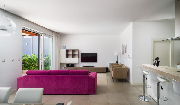 Open space living room with comfortable sofa, dining table and kitchen island in a luxury family villa with private pool and Wi-Fi