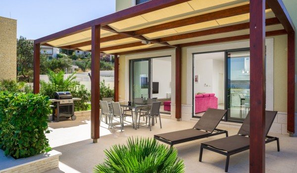 Outdoor table and deck chairs on the terrace of a luxury family villa for vacation at the beach in Ciovo