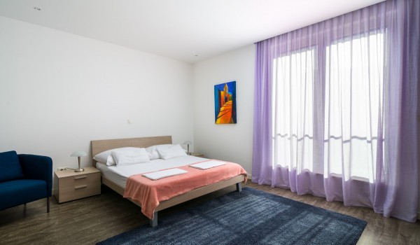 Seating area next to the double bed in a bedroom of a luxury family villa for vacation at the beach in Ciovo