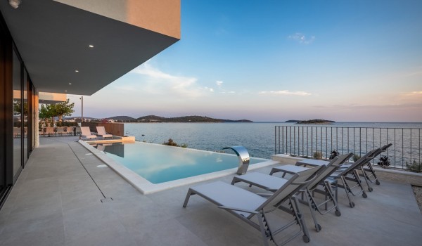 The outdoor terrace of the luxury villa Supreme Rogoznica 2 with a private heated pool surrounded by deckchairs for sunbathing