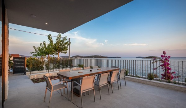 Outdoor covered terrace with dining table and chairs and sea view in the luxury villa Supreme Rogoznica 2 in Rogoznica