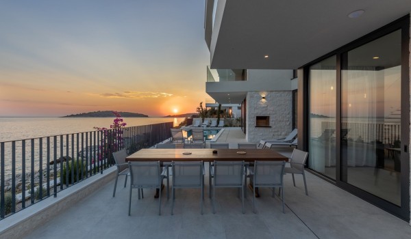 A view of the outdoor terrace with a dining table and chairs and a view of the sea in the luxury family vacation villa Supreme Rogoznica 2 in Rogoznica