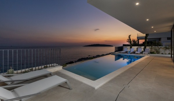 The view from the outdoor terrace of the sea and the private heated pool surrounded by deckchairs in the luxurious holiday villa Supreme Rogoznica 2 in Rogoznica