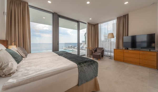 A spacious bedroom with a double bed, armchair, LCD TV and direct access to the outdoor terrace of the luxury villa Supreme Rogoznica 2 in Rogoznica