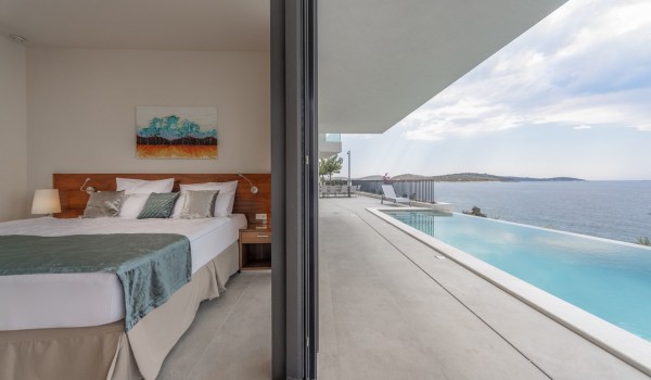 View of the double bed in the bedroom and the outdoor terrace with private pool in the luxury villa Supreme Rogoznica 2 in Rogoznica