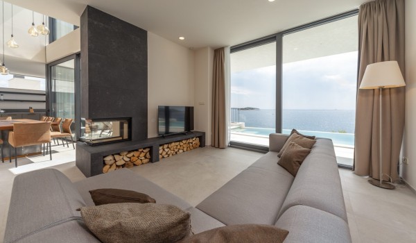 Living room with corner sofa, LCD TV, indoor fireplace and direct access to the outdoor terrace of the luxury villa Supreme Rogoznica 2 in Rogoznica