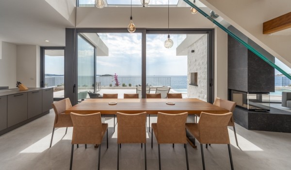 Dining table with chairs and a view of the sea and the outdoor terrace of the luxury villa for rent and vacation Supreme Rogoznica 2 in Rogoznica