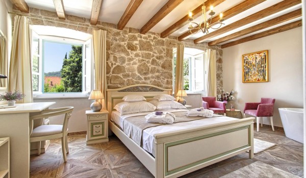 Air conditioned bedroom with a king size bed and stone wall in the luxury Dubrovnik villa with private garden and a jacuzzi