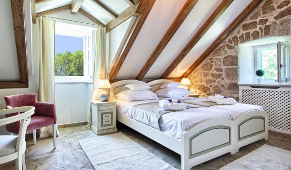 Air conditioned bedroom with a king-size bed in the attic of the historic stone villa Cavtat Iliria for a family rent and vacation near Dubrovnik