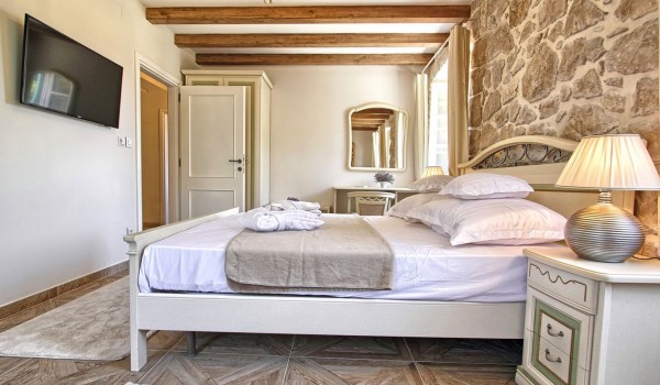 King-size bed and an LCD TV in a bedroom of a Croatia luxury vacation villa for rent with jacuzzi and private garden near Dubrovnik