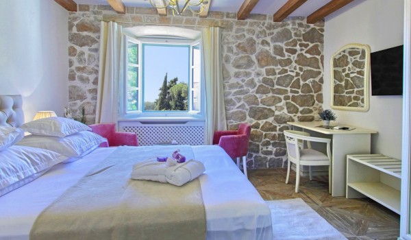 Air conditioned bedroom with a king size bed, LCD TV and a stone wall in the luxury Dubrovnik villa with private garden and a jacuzzi