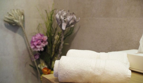 A Towel detail with flower decorations in the luxurious bathroom with a shower in the private stone villa Cavtat Iliria near the sea