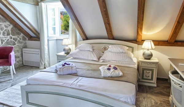 Air conditioned bedroom with a king size bed, LCD TV and a stone wall in the attic of the private Dubrovnik villa with a jacuzzi near the sea