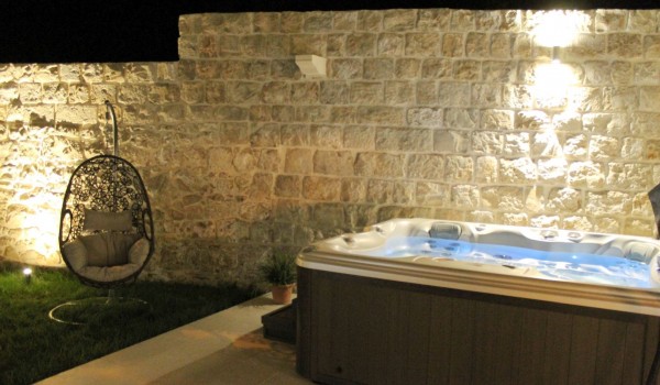 Evening view of the fenced private garden with a terrace and jacuzzi in front of the luxury sea-view Dubrovnik villa for rent and vacation