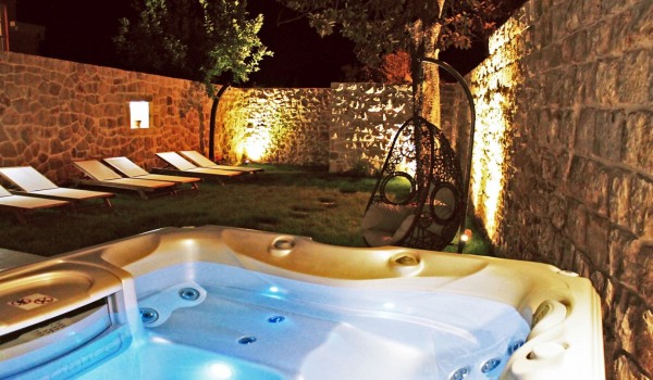 Evening view of the fenced private garden with a jacuzzi and sun loungers of the luxury sea-view rental villa near Dubrovnik