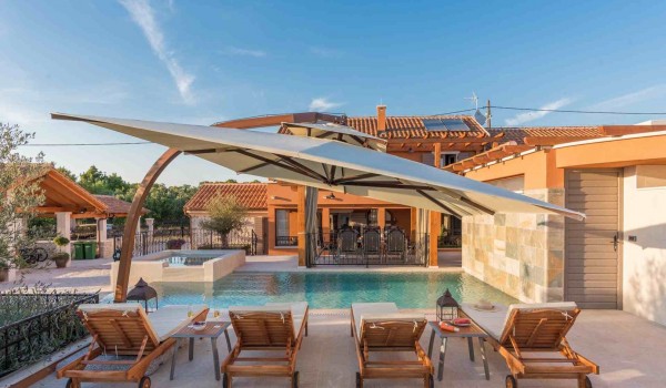Sun beds and parasol by the heated pool of a Croatia luxury pet-friendly villa for family vacation in Skradin