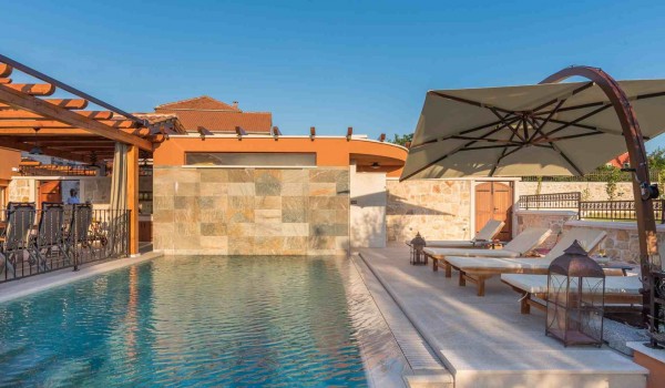 Sun beds and parasol by the heated pool of a Croatia luxury pet-friendly villa for family vacation in Skradin