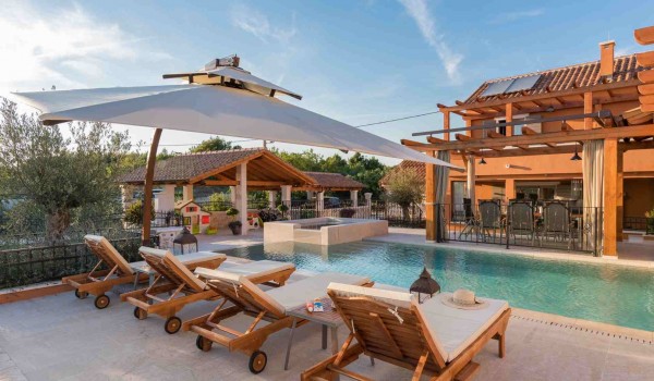 Sun beds and parasol by the heated pool of a Croatia luxury pet-friendly villa for family vacation in Skradin