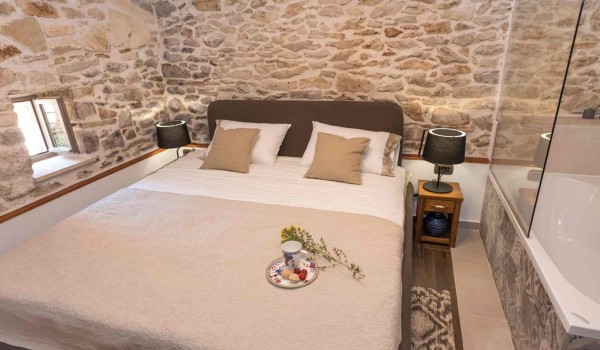 Bathtub and king size bed in a bedroom of a luxury pet-friendly villa for family vacation in Skradin