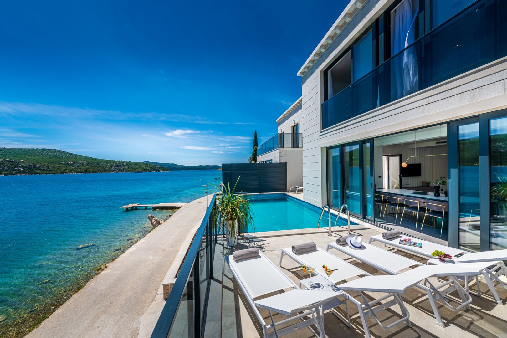 Croatian luxury beachfront villa Zaira with private pool surrounded by deckchairs and sundeck for vacation and rent