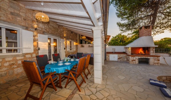 Outdoor grill and dining table on the terrace of the Dalmatian stone house for family vacation on Brac island