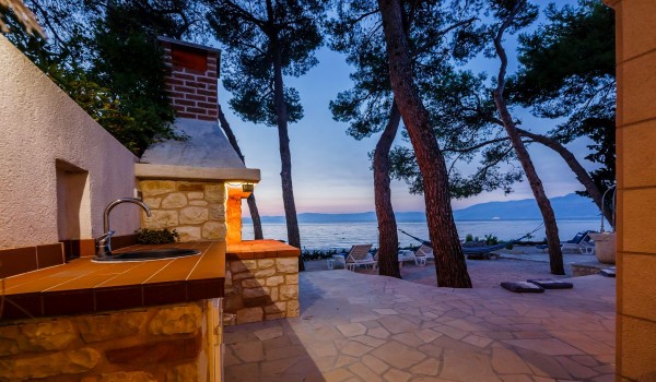 Outdoor grill and lounge chairs on the terrace of the Brac stone house with sea view