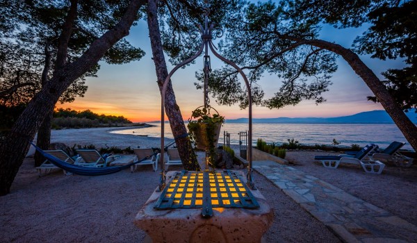 Well and deck chairs on the sandy courtyard of the Dalmatian stone house by the sea