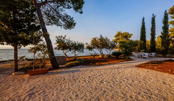Sandy and pebbly courtyard and landscaped garden of the Croatia beachfront villa for family vacation on Brac island