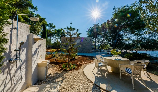 Outdoor shower and seating area in the landscaped garden of the Croatia traditional stone villa at the beach on Brac island