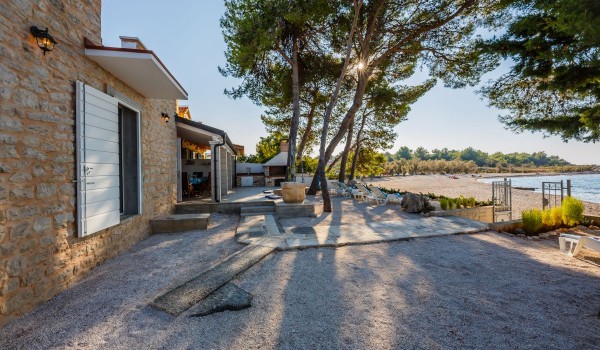 Sandy and pebbly courtyard of the traditional Dalmatian stone villa for family vacation by the sea