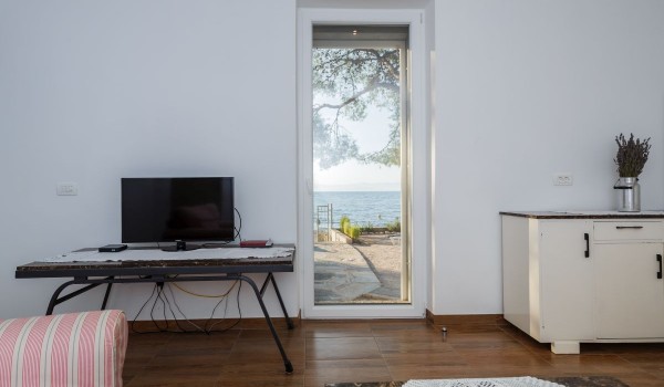 TV in the living room with direct entrance to the terrace of the traditional stone villa for family vacation by the sea
