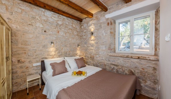 Double bed in a bedroom of a Dalmatian stone house with sea view on Brac island