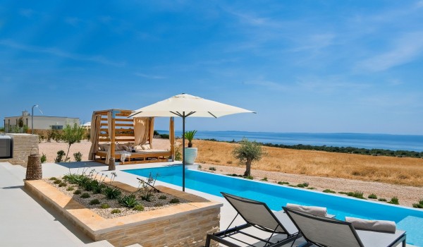 A spacious terrace with a sun deck and a lounge bed for resting next to the large infinity pool of the private Croatian villa Summer Dream Privacy Novalja for rent on the island of Pag with p