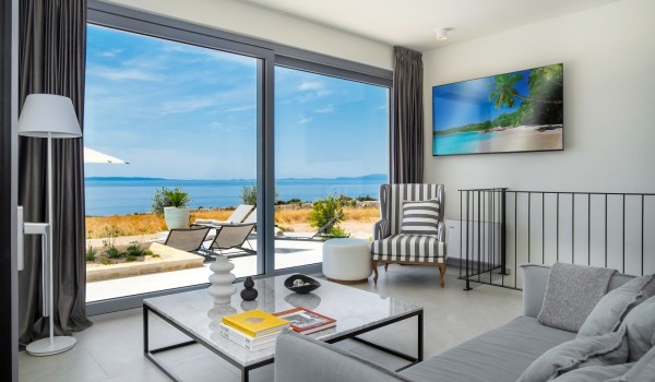 View from the living room to the terrace with a sunbed and deckchairs of the private holiday villa with pool Summer Dream Privacy Novalja on the island of Pag with chef service on request