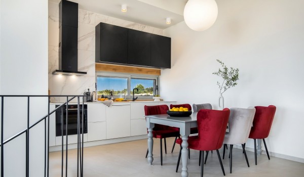 A view of the elegant interior of a modern kitchen equipped with high-end appliances and a dining table in a private family villa for rent with a swimming pool on the island of Pag by the sea