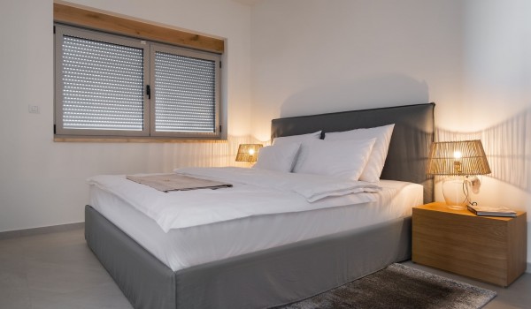 A spacious air-conditioned bedroom with a king-size bed in a private villa for rent with a jacuzzi and a sauna on the island of Pag in Novalja