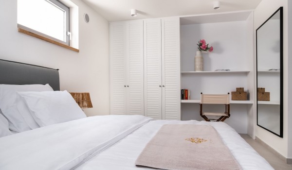 A spacious bedroom with a king-size bed, a lounge chair and a SMART TV in a Croatian family villa with a swimming pool next to the beach for a vacation on the island of Pag