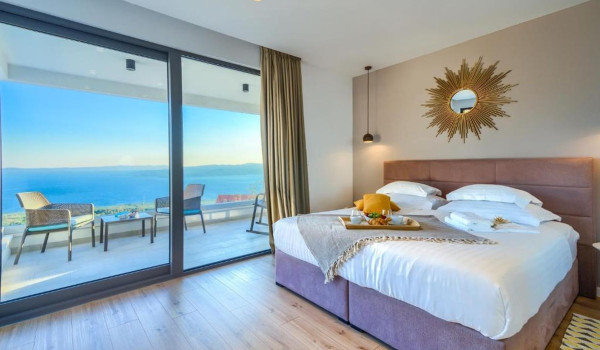 A spacious modern bedroom with access to a terrace with a seating area and a view of the Brač channel